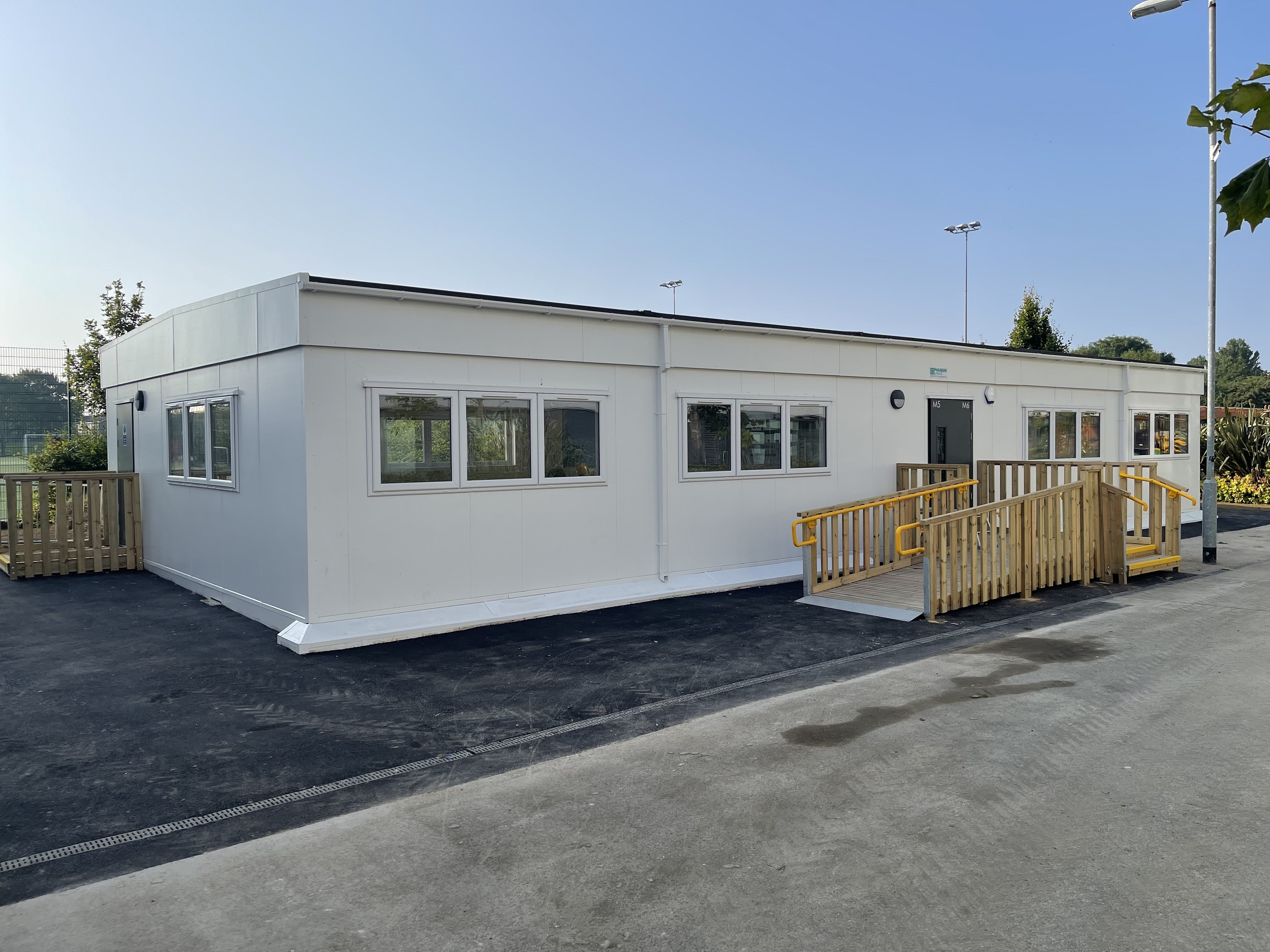 Single storey five bay modular building with wooden ramp leading to the entrance.